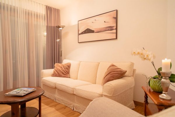 landhaus-apartments-appartement-11-wohnzimmer-sofa-orchidee Wohnzimmer im Apartment #11 mit Sofa und Blumendeko